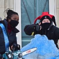 person holding chainsaw, person with thumbs up, and michigan ice sculpture
